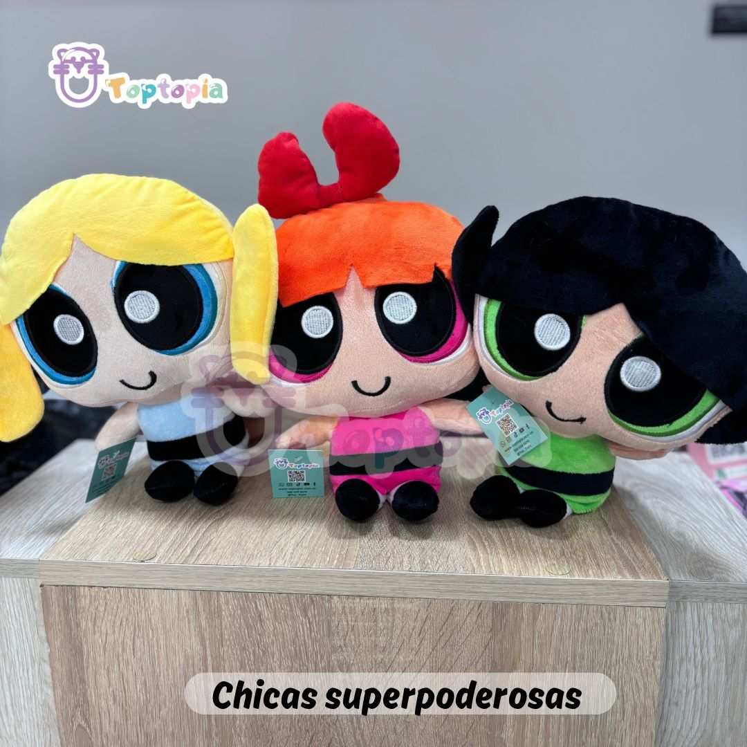 Set de peluches de Las Chicas Superpoderosas con Bombón, Burbuja y Bellota, cada una con su vestido y colores característicos, exhibidas juntas sobre fondo de tienda de juguetes.